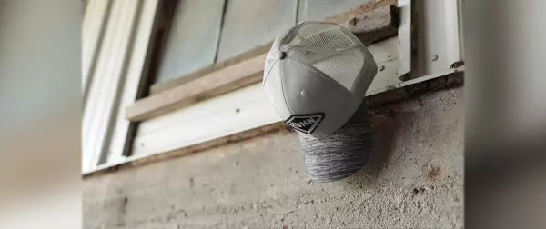 Grey KUHN hat hangs from a barn window